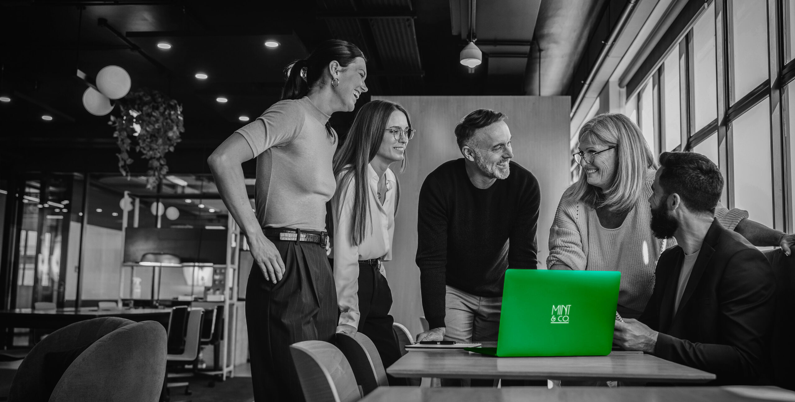 Marketing team around a laptop with Mint & Co. logo, real estate strategy