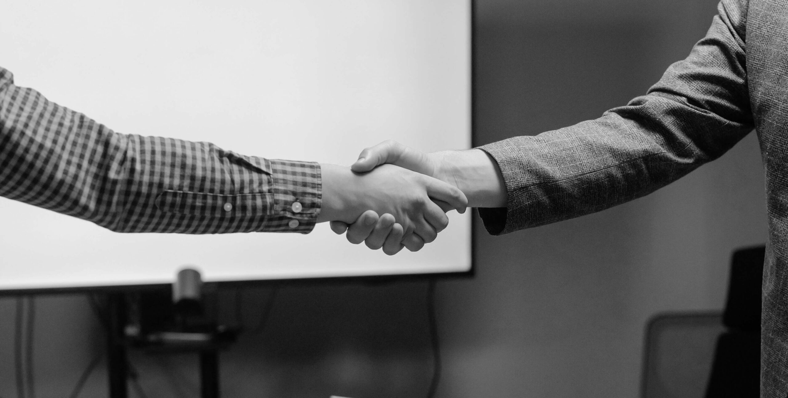 Business handshake in front of a presentation screen, real estate partnership