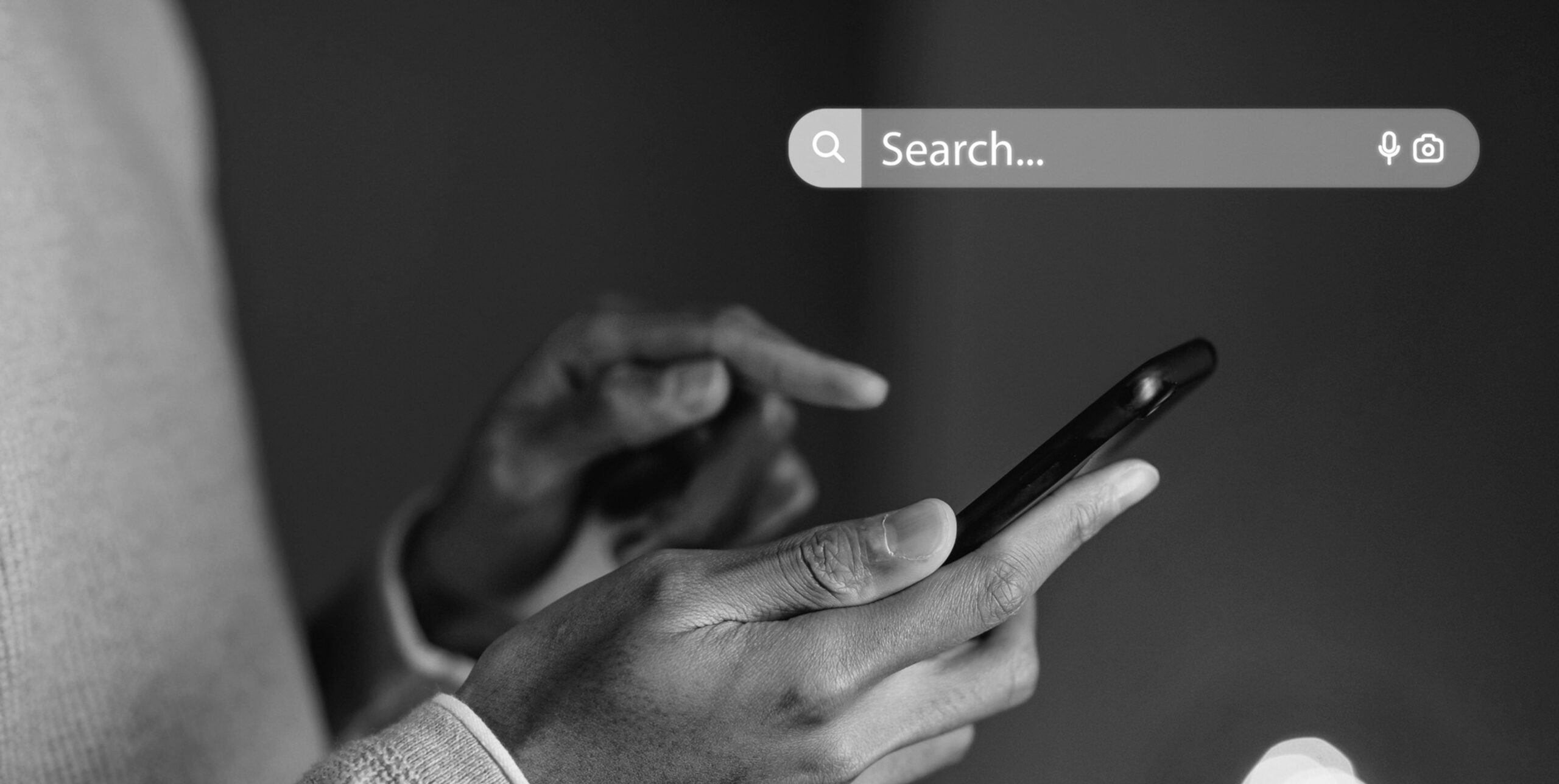 Hands holding a smartphone below a search bar, online property search