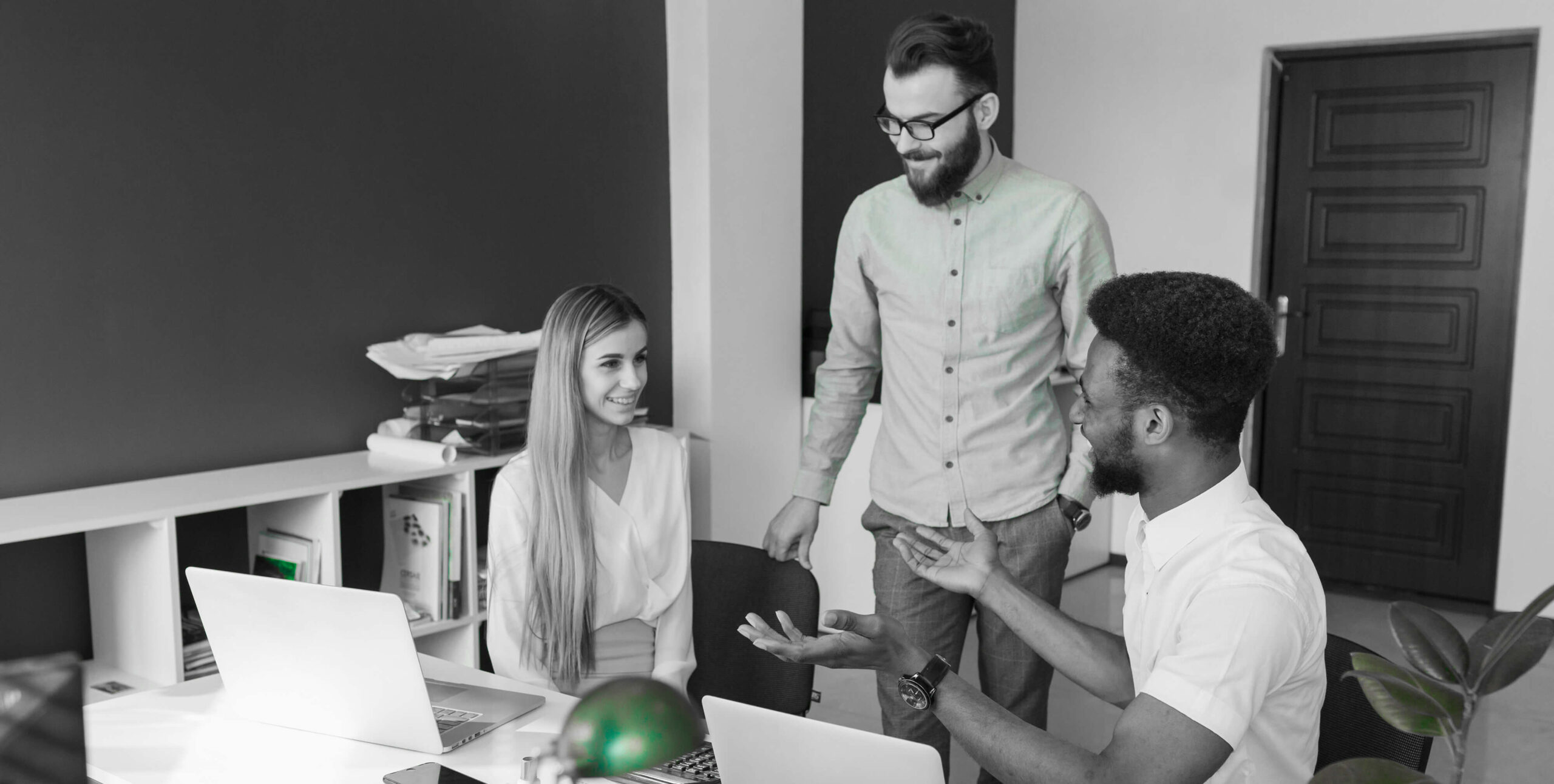 Colleagues chatting near laptops, real estate marketing team collaboration