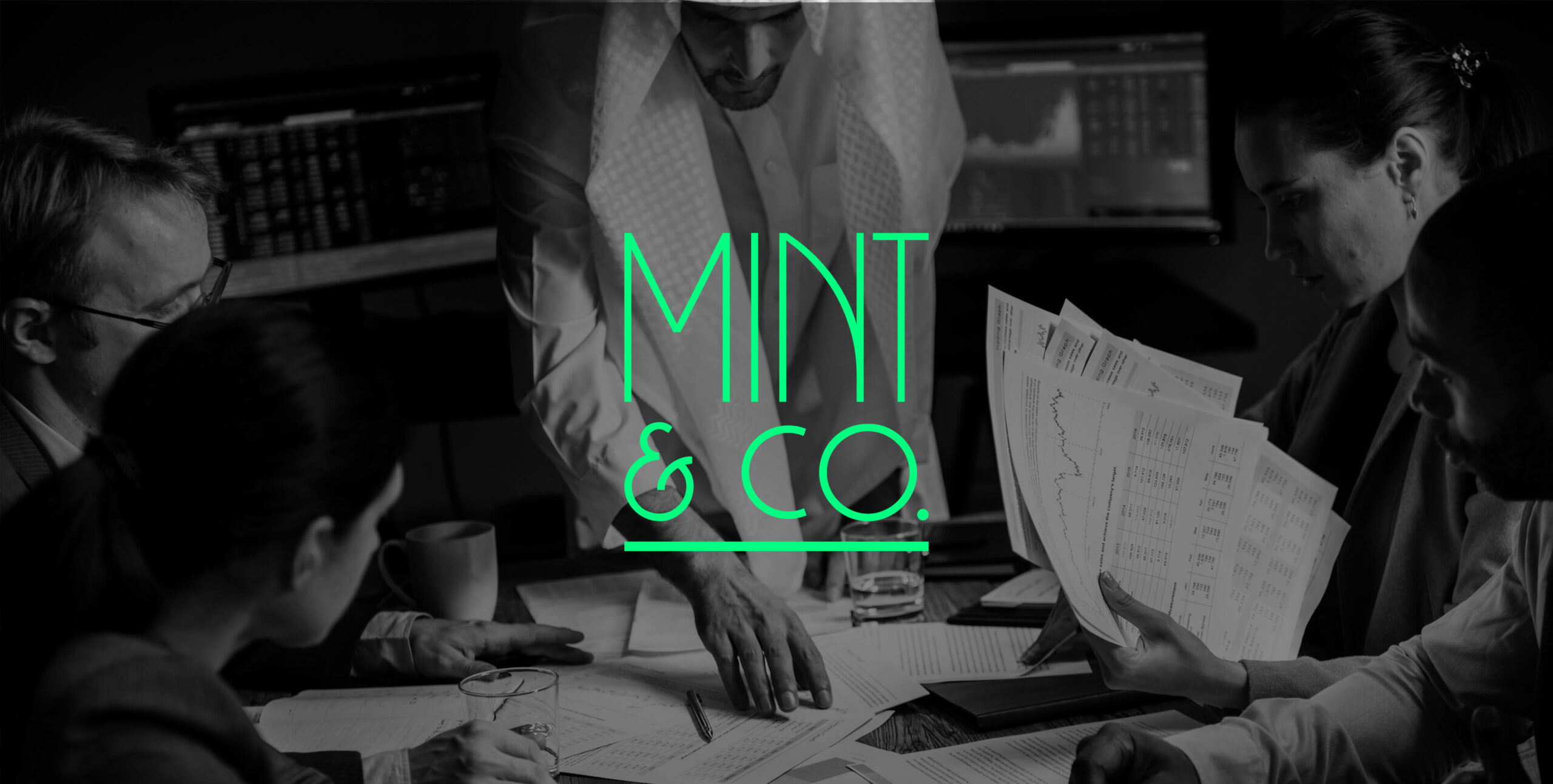 Team reviewing financial charts with Mint & Co. logo overlaid