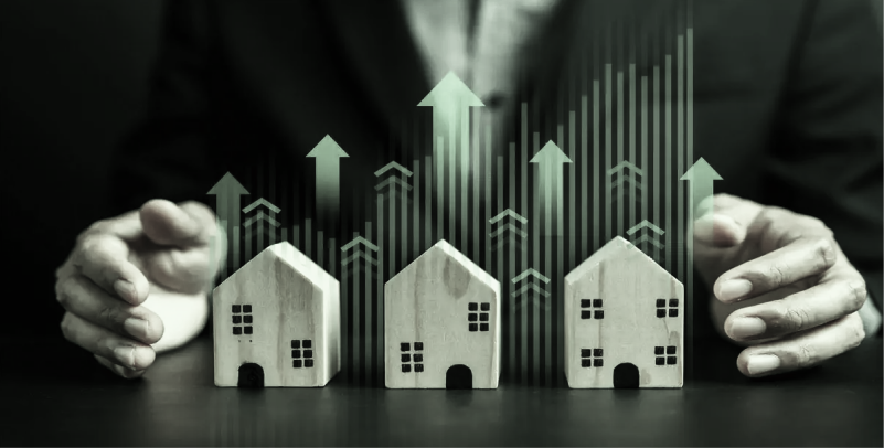 Businessman shielding house models with growth arrows, real estate market growth